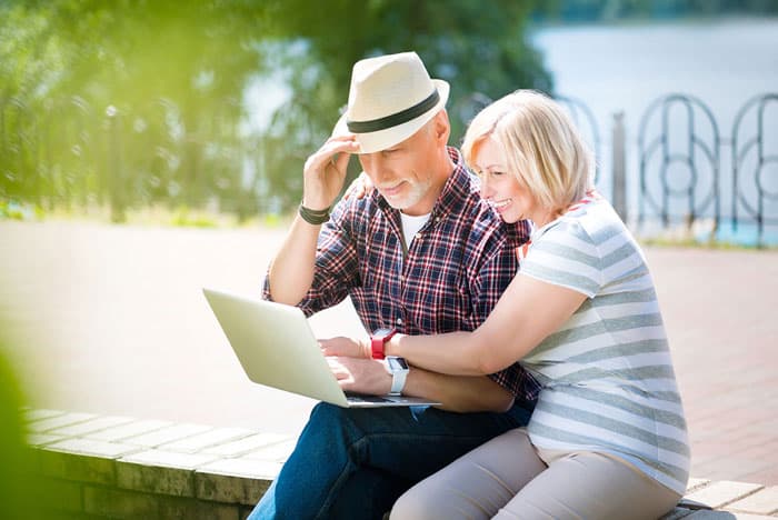 older couple looking at a laptop outside