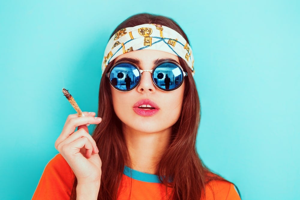 Hippie girl smoking weed and wearing sunglasses